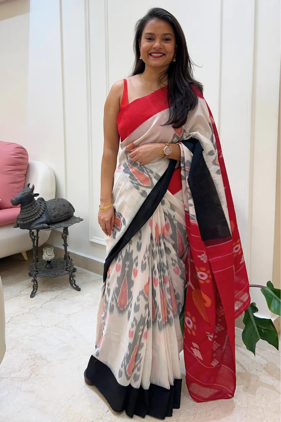 Woman wearing a handloom ikkat saree with a red blouse in an indoor setting