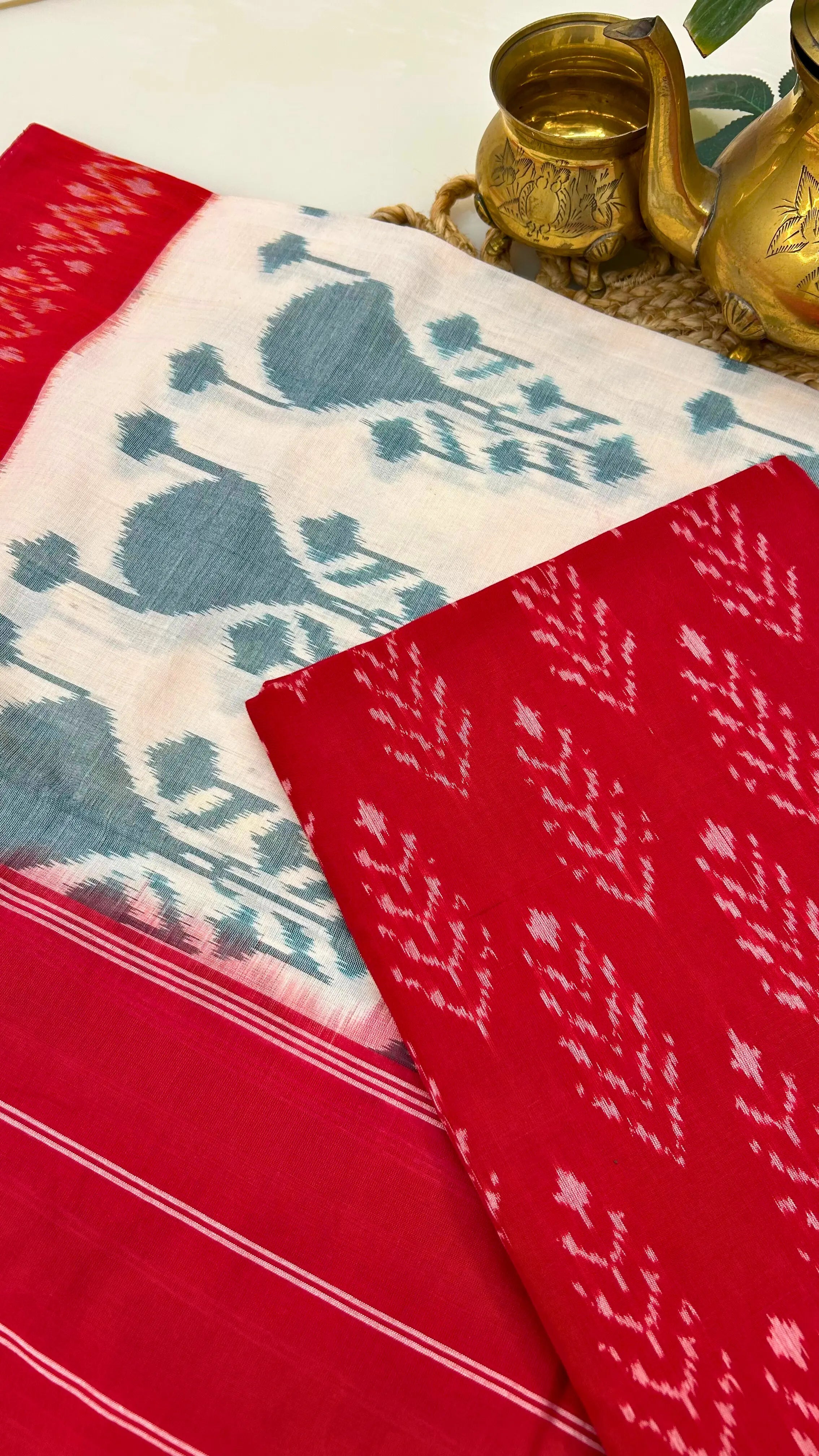 Close-up of red Ikkat cotton fabric with resist-dyed white motifs, highlighting handloom texture and craftsmanship.
