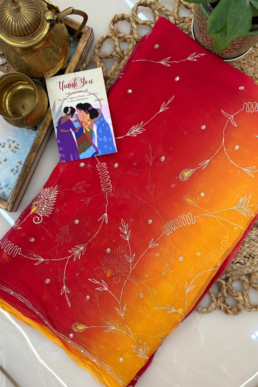 Red and orange fabric with white floral patterns on a textured surface.