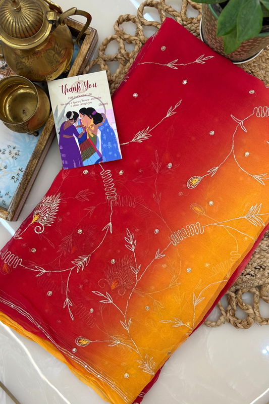 Red and orange fabric with white floral patterns on a textured surface.