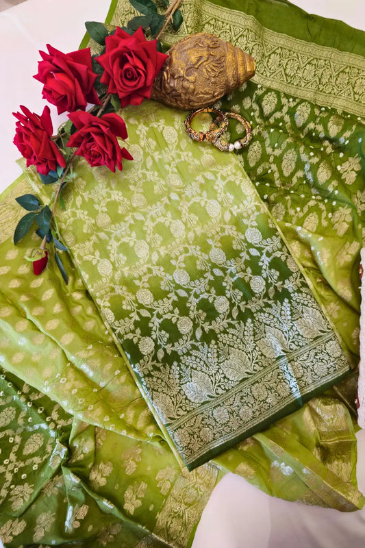 Green embroidered fabric with red roses and jewelry on a white surface