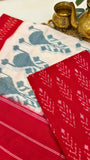 Close-up of red Ikkat cotton fabric with resist-dyed white motifs, highlighting handloom texture and craftsmanship.