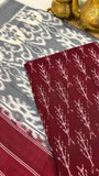 Close-up of maroon Ikkat cotton fabric with traditional resist-dyed motifs.